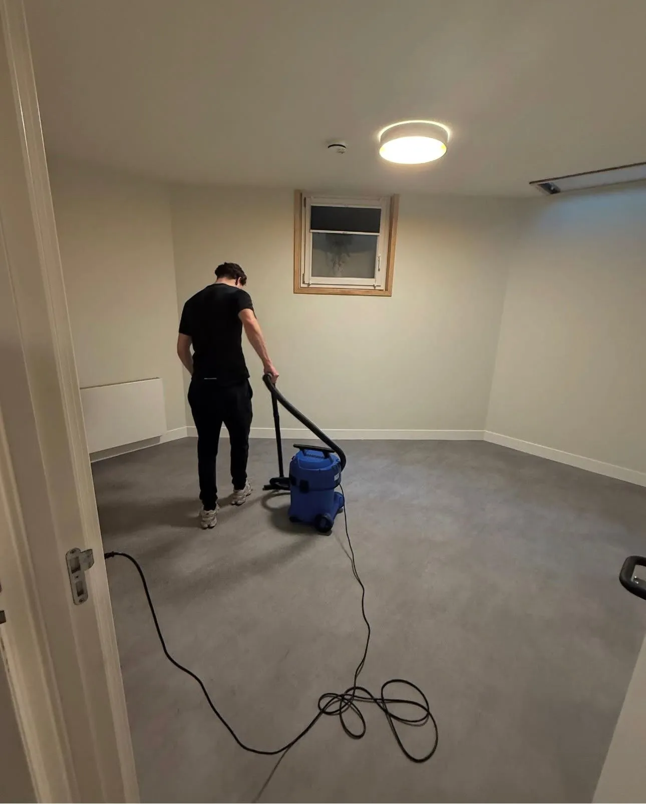 Medewerker stofzuigt een lege ruimte bij oplevering